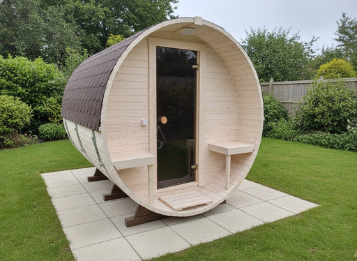 Wooden barrel-shaped sauna in a garden setting with greenery around.