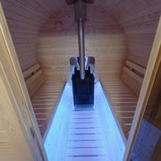 Wooden sauna with benches and a metal shovel on a reflective surface.